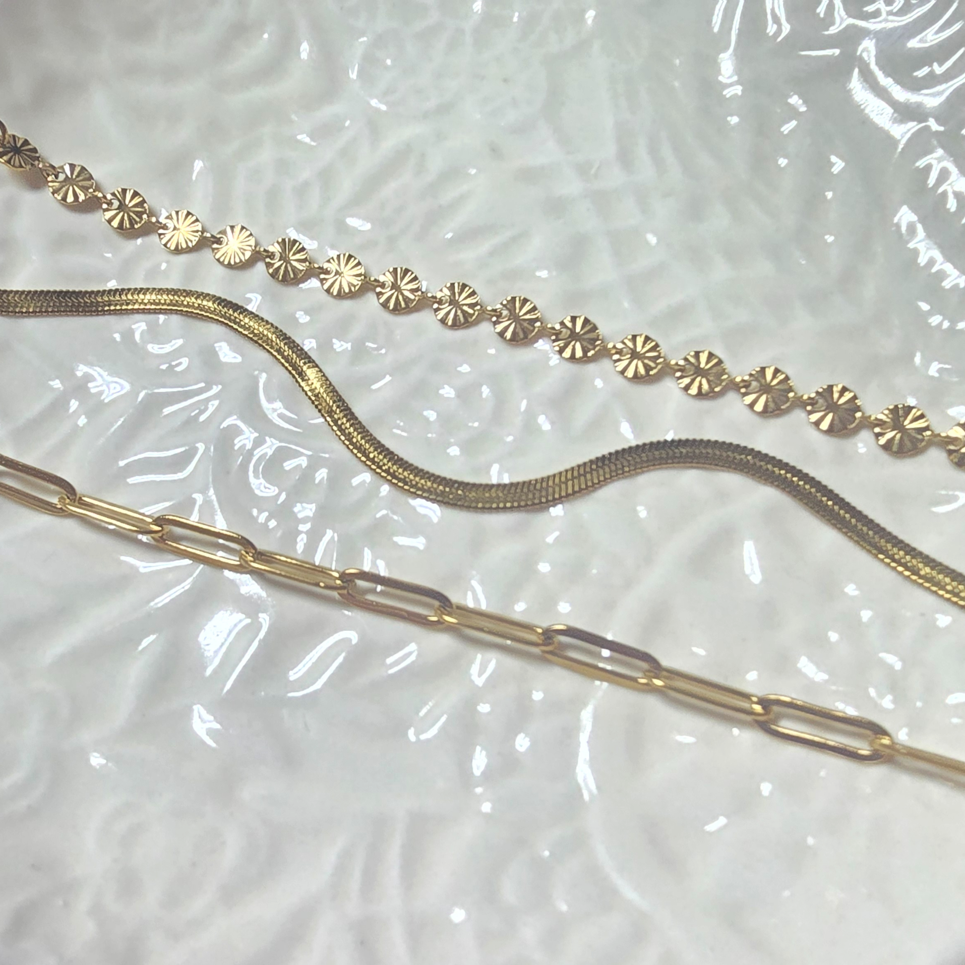 three gold bracelets on a textured surface