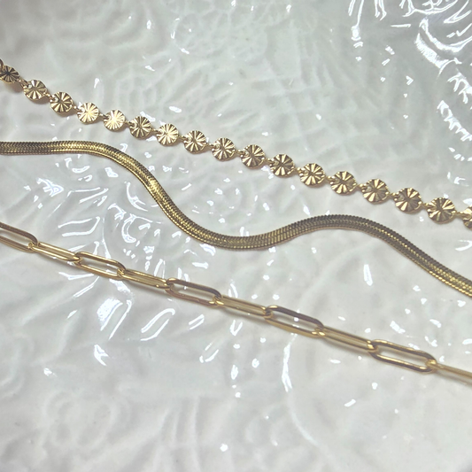 three gold bracelets on a textured surface