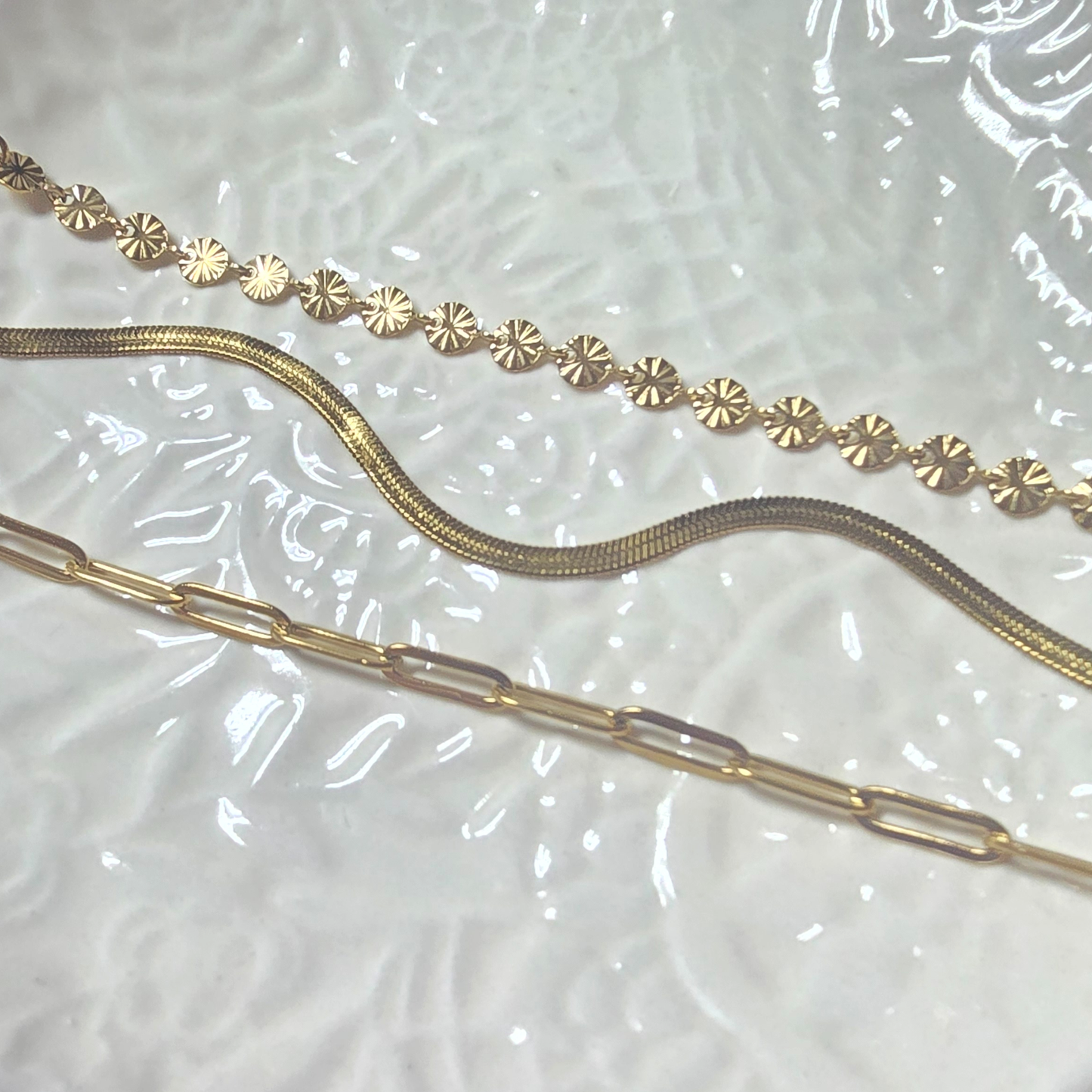 three gold bracelets on a textured surface